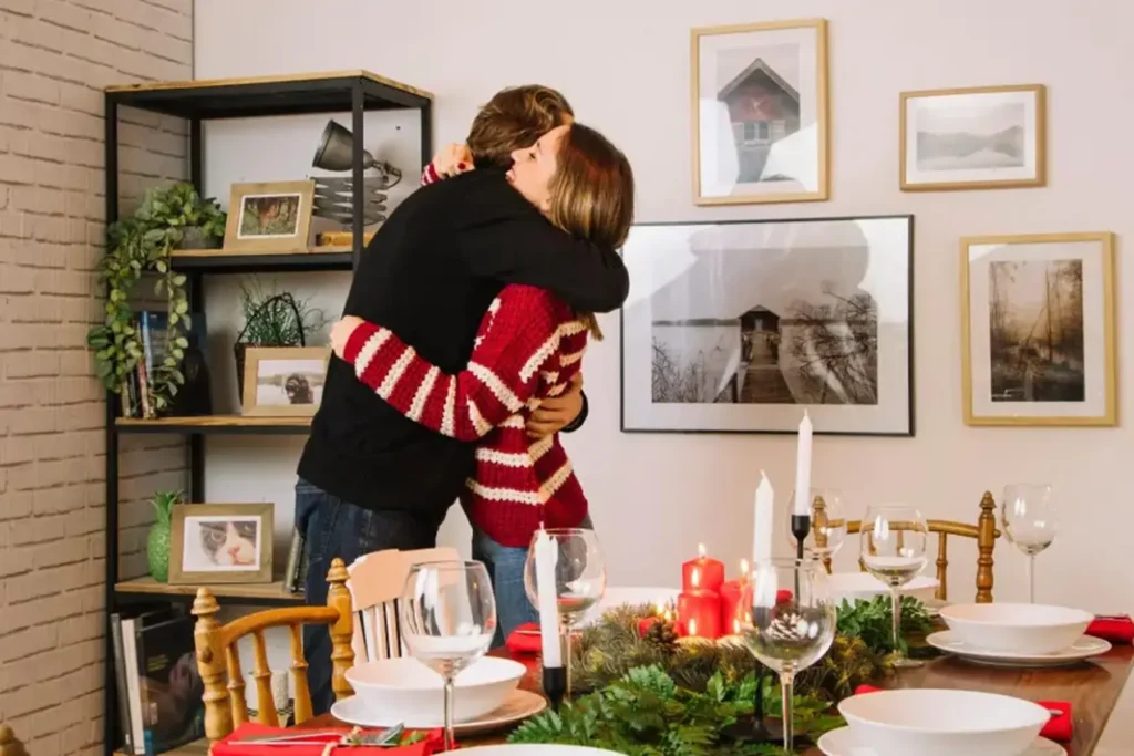 man and woman hugging in front of a beautifully set Christmas dinner table