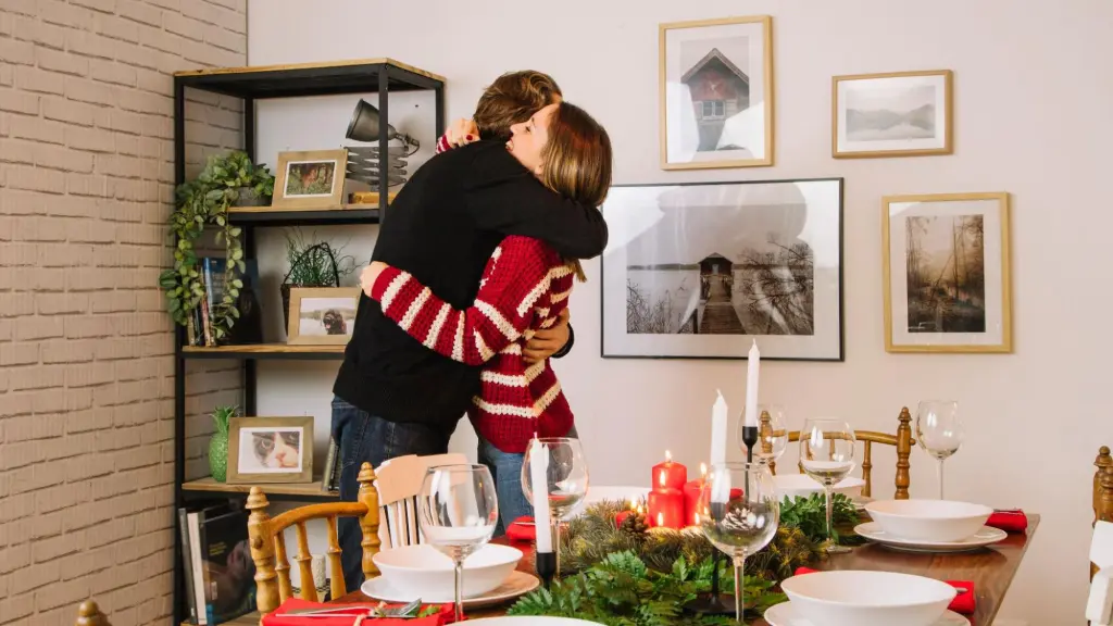 man and woman hugging in front of a beautifully set Christmas dinner table